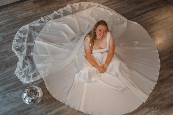 Modell sitzt mit ausgebreitetem Kleid auf dem Boden